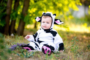 Year of the bull. A child in a fancy dress of a bull on a meadow smiles cute. Kid in Halloween Cow...