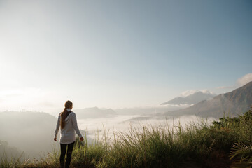 Beautiful woman wlking on  the top of Mount Batur, Bali, Indonesia. Mountain hiking at sunrise