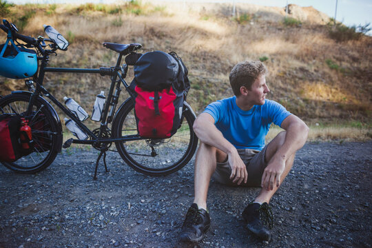 Young, fit man resting from bicycle touring expedition at sunrise