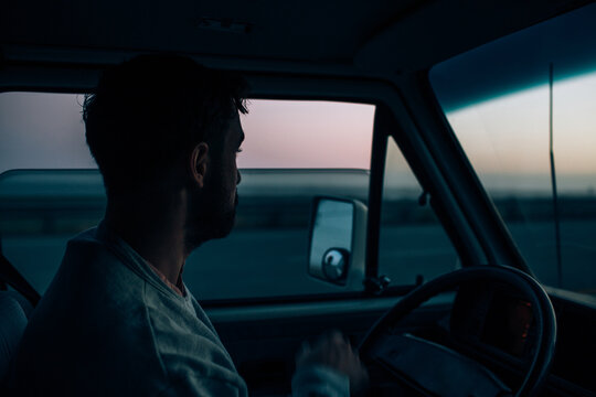 A weary traveler looks out the window at dusk