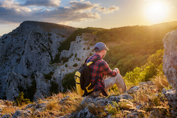 Adventurous man is on top of the mountain and enjoying the beautiful view during a vibrant sunset