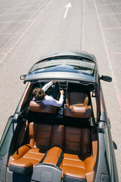 Young man driving a convertible car on a road dring a sunny day