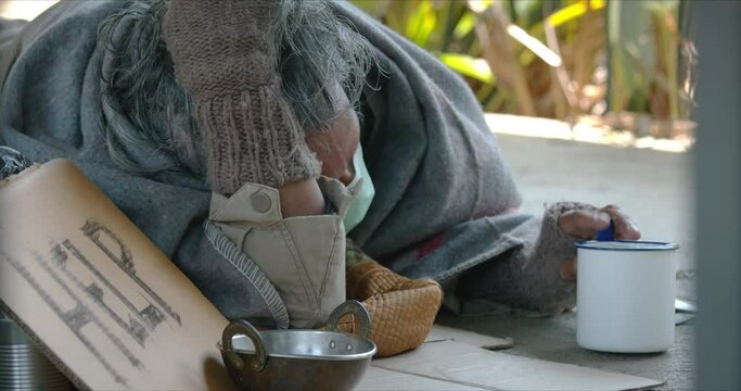 Homeless man is lying and holding a cup to ask for money