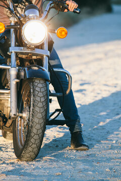Man riding a motorbike on a dirt road - Close up shot of the front of the motorbike and leg