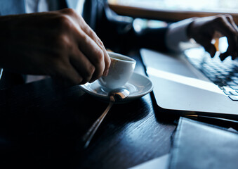 business man in a cafe at the table in front of a laptop work a cup of coffee at the table communication technology