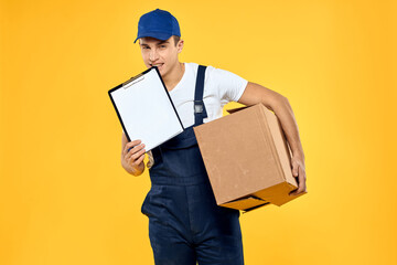 Working man in uniform with box hand delivery loading service yellow background