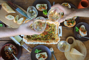 Flat-lay of people eating and drinking wine. Casserole with cheese and mushrooms. Mushroom tart