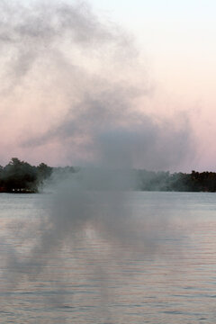 Smoke Drifting over the Lake at Sunset
