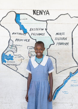 School girl standing in front of map of Kenya.