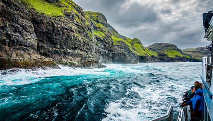 Blurred tourists observe the spectacular Vestmanna cliffs in Faroe Islands