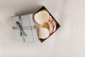 Gift box with a bow and rose petals