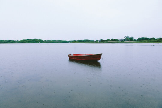 Orange Boat Sitting In The Middle Of Rainy Water