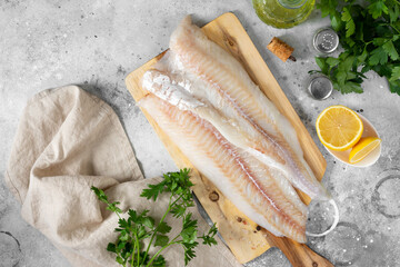 Cod fillet. Raw cod fillet on a chopping Board on a light gray kitchen table. Preparation for cooking fish. Top view