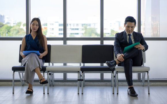 Asian Business People Waiting For Job Interview By Sitting Spaced Apart. Concept Of New Normal Office Business During Coronavirus Pandemic Outbreak.