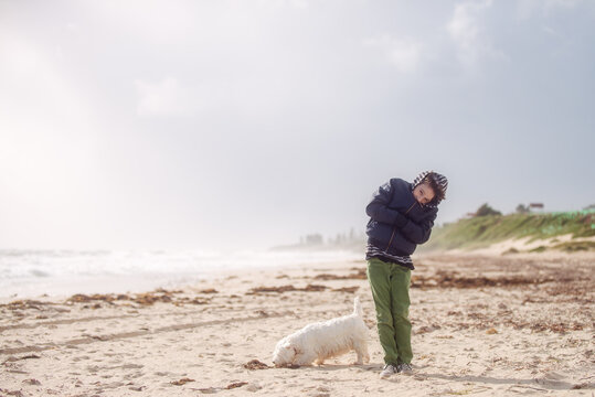 Boy with his dog at the beach on a super windy day in winter