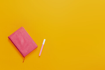 School supplies flat lay on the orange background. Pink notebook and colorful marker pens and stickers.