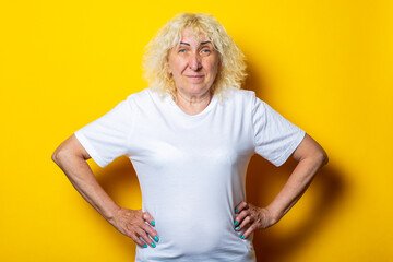 Old woman in casual white t-shirt on yellow background
