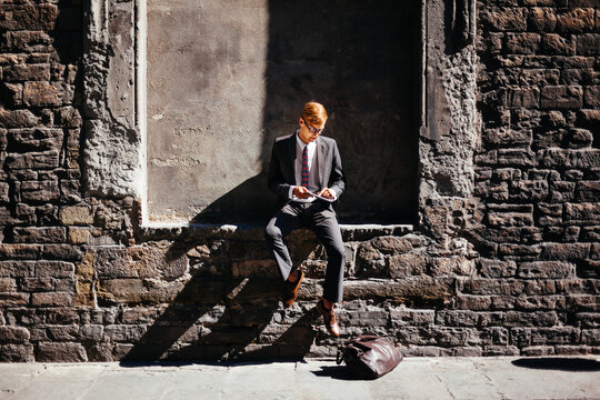 Smart Businessman Using a Digital Tablet in Front a Brik Wall