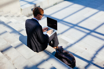 Smart Businessman Using Laptop for His Work Outdoor Sitting on the Stairs