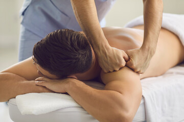 Young man getting professional remedial body massage in massage room or health center