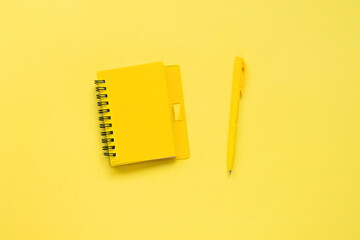 Creative monochrome flat lay of bloggers workspace. Top view of yellow notepad and pen. Yellow background, place for text.