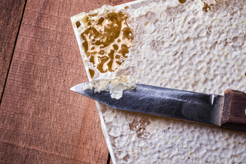 knife on honeycomb with honey on a wooden background