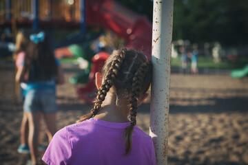 Recess: Lonely Girl Leans Against Swingset Watching Others