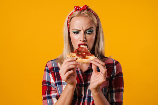 Image of displeased charming pinup girl grimacing while eating pizza
