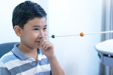 Asian boy using  Brock string to exercise their eye muscles, Eye vision therapy