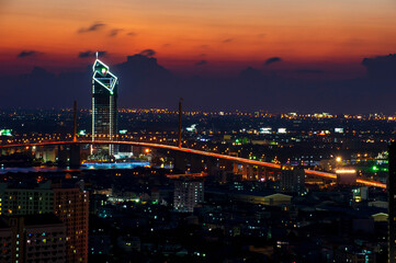 Obraz premium Long-speed photograph of the Industrial Ring Expressway and Bhumibol Bridge. Cityscape Bangkok at night, buildings in the central business district.