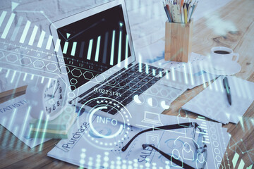 Computer on desktop in office with technology theme hologram. Double exposure. Tech concept.