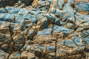 Close up view bright vivid orange brown yellow stone rock shabby cliff cracks texture mountains. Concept of geology, beauty power in nature. Natural summer composition landmark background design