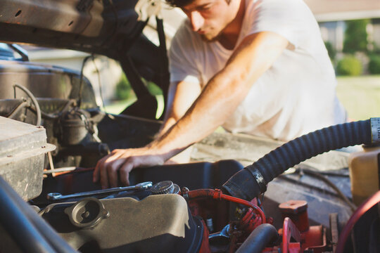 Young man working on motor of an old pickup