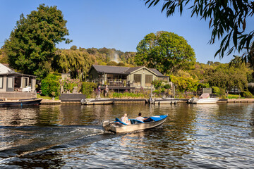 Boat sailing past a riverside house in Henley-on-Thames, England.