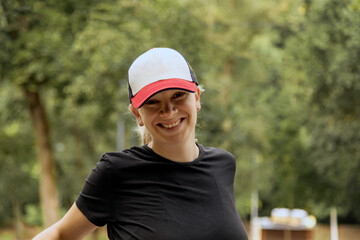 Portrait of a young pregnant woman in sportswear and a baseball cap on a walk in the city park. Close-up, selective focus.
