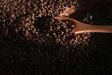 Coffee beans in wooden spoon, under beam of light