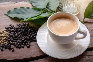 Coffee cup, coffee beans decorated with coffee leaves on wooden table,.top view