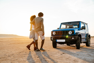 Image of african american couple walking while travelling with car