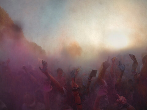 Hand of Crowd throwing holi powder in the air