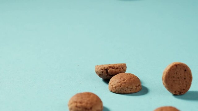 Scattered traditional dutch cookies kruidnoten gingersnap over blue background. St Nicholas day Sinterklaas in December, children holiday in Netherlands and Belgium. Full HD video, 100 fps slow motion