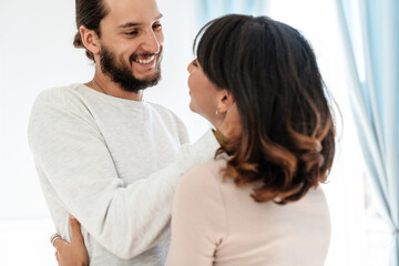 Image of romantic joyful couple smiling and hugging while standing