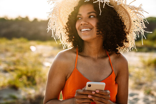 Smiling young african woman using mobile phone - Powered by Adobe