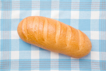 Fresh white bread on checkered kitchen towel. Closeup. Top down view.