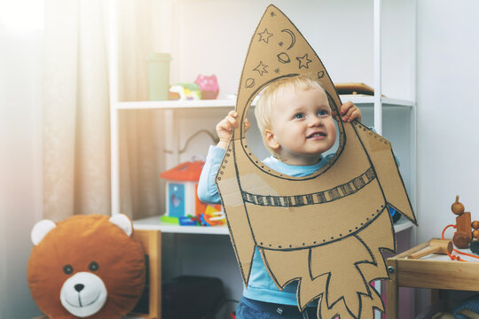 little boy playing with cardboard spaceship at home. imagination and dream profession concept