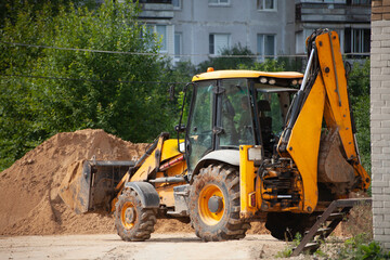An excavator at a construction site loads sand.