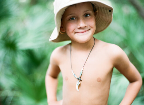 Tan boy in bucket hat with an Alligator tooth necklace in the wild palms