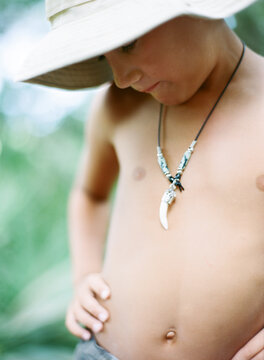 Tan boy in bucket hat with an Alligator tooth necklace in the wild palms
