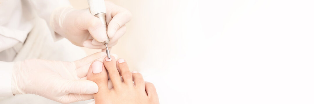 Beautiful salon procedure with pink pedicure on towel background. For decoration design. Healthcare. Woman body care. Spa treatment. White background. Nail machine polish. Medical