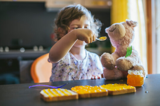 Little girl playing with her teddy bear and food