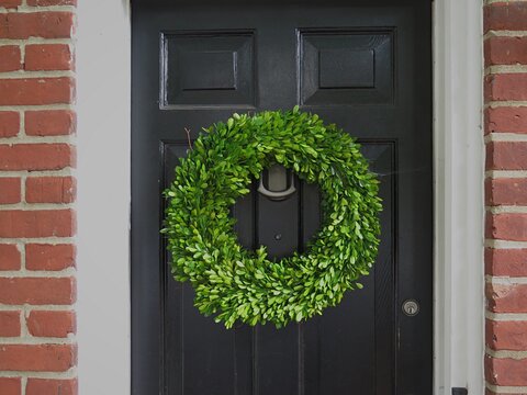 A green holly holiday wreath on a black door